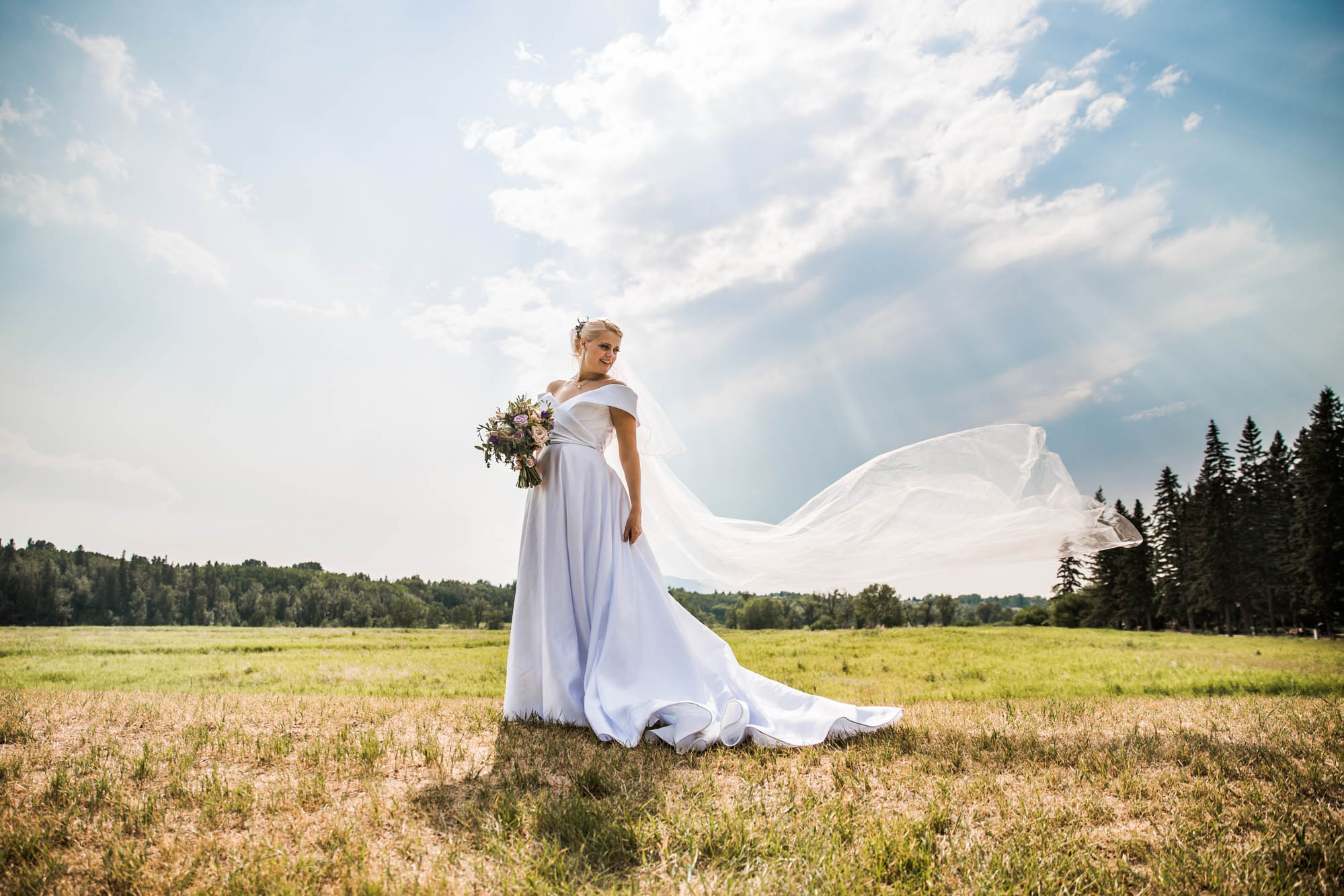 Calgary wedding and family photographer, bride in front of beautiful sky at Fish Creek Park in Calgary