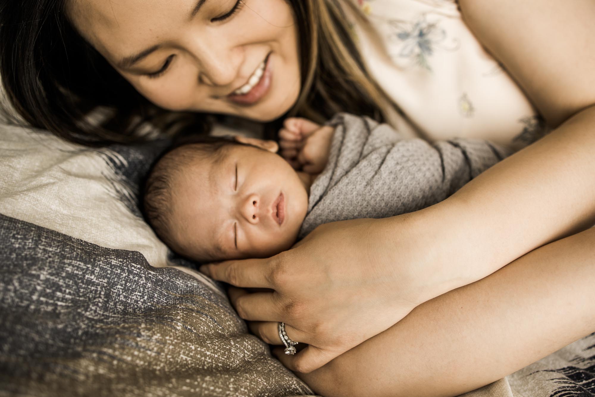 Calgary newborn and maternity lifestyle photographer, newborn baby in his parent's arms during an in-home lifestyle newborn photo session