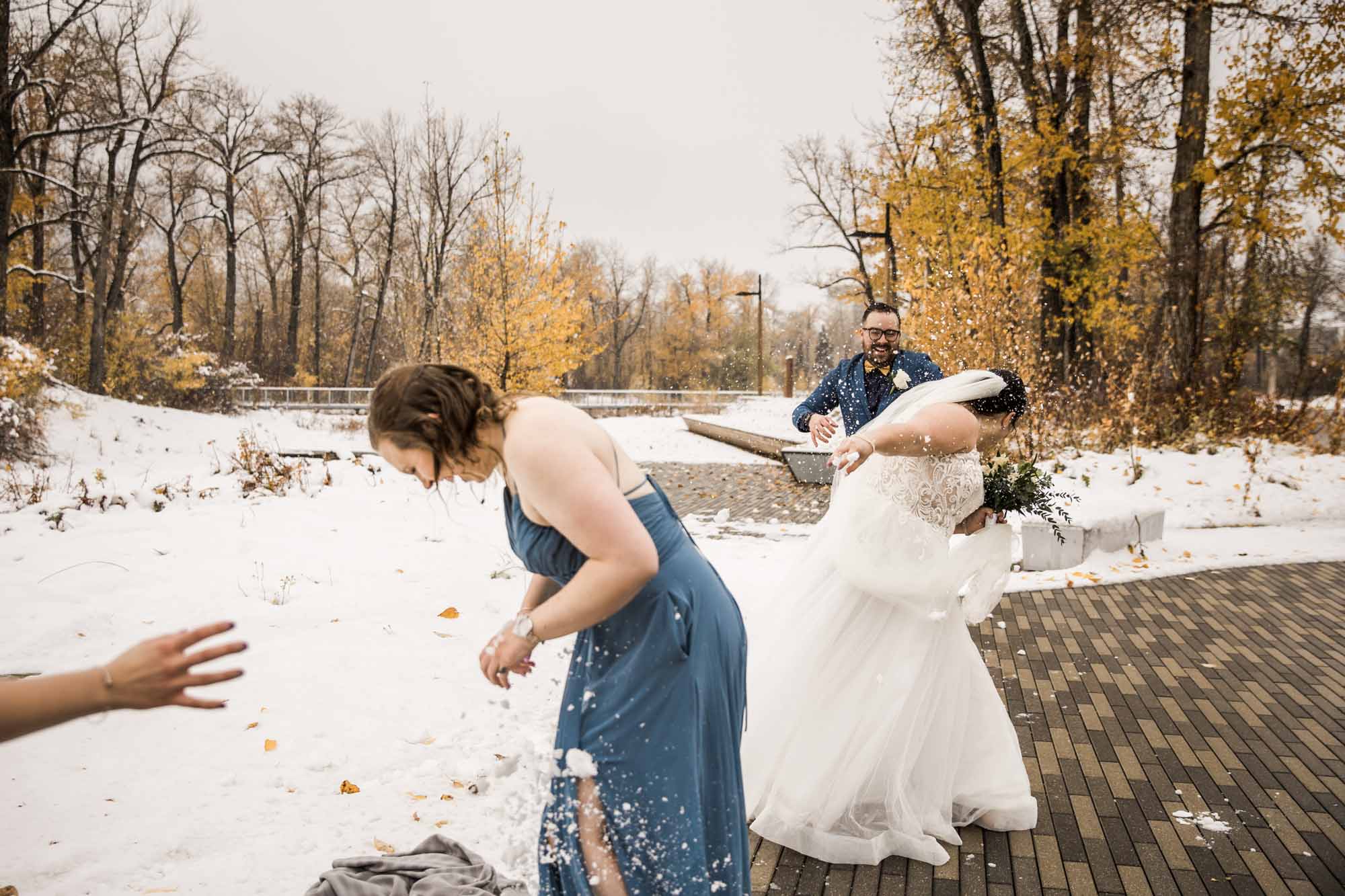 Calgary wedding photographer, bride in her dress with her bridal flowers and groom on their wedding day at St Patrick's Island, winter snow and fall leaves