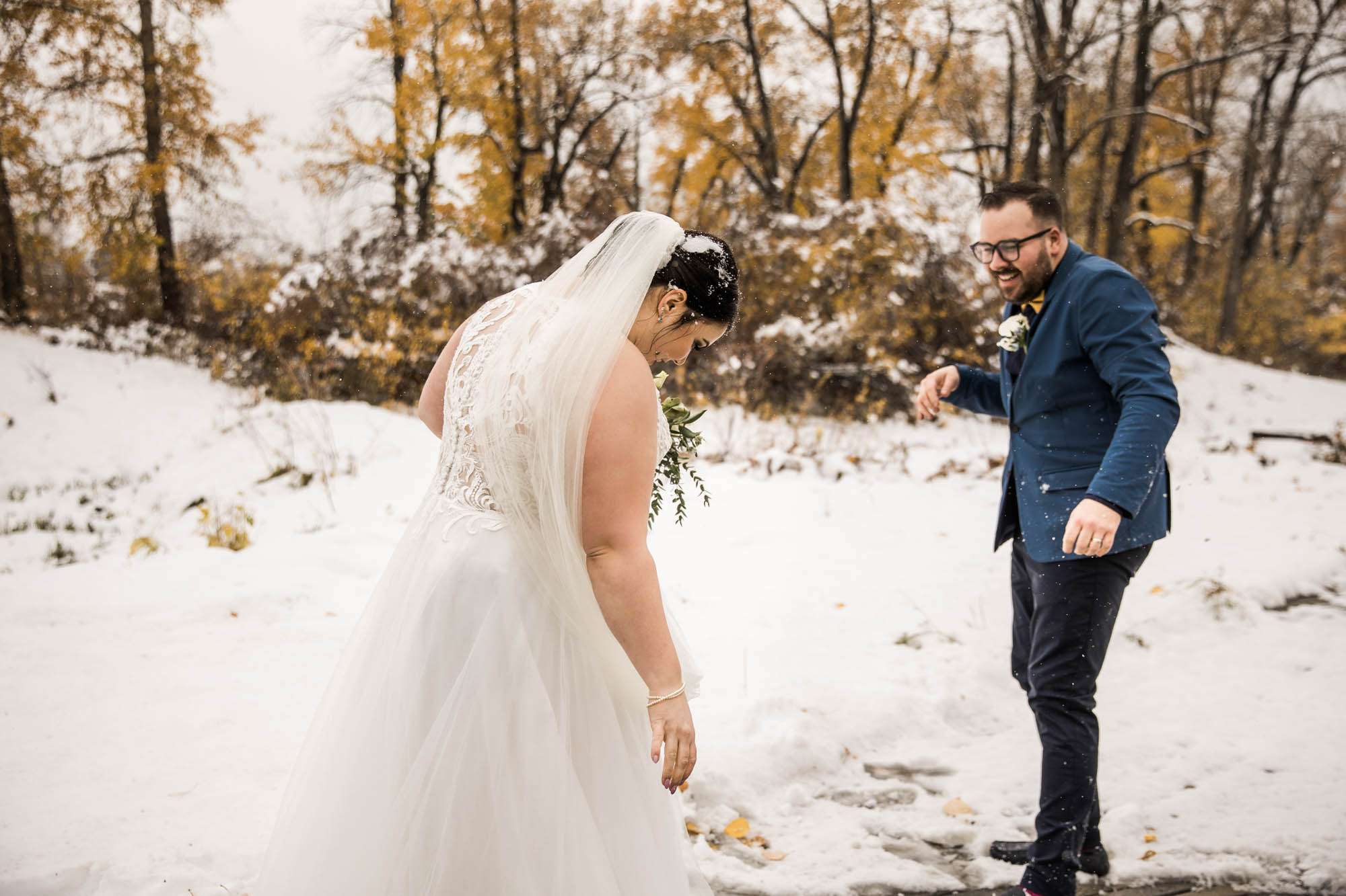 Calgary wedding photographer, bride in her dress with her bridal flowers and groom on their wedding day at St Patrick's Island, winter snow and fall leaves