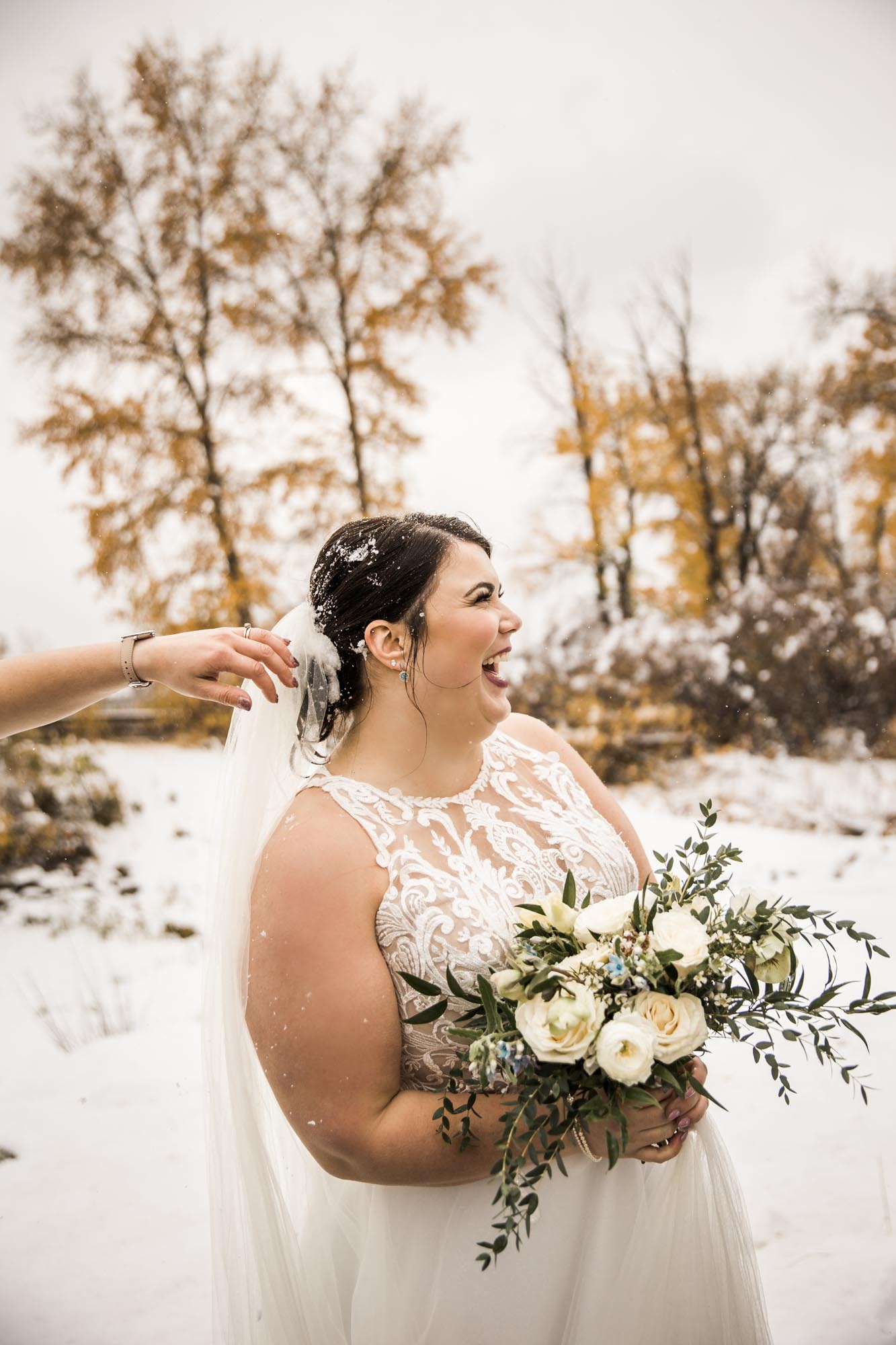 Calgary wedding photographer, bride in her dress with her bridal flowers and groom on their wedding day at St Patrick's Island, winter snow and fall leaves